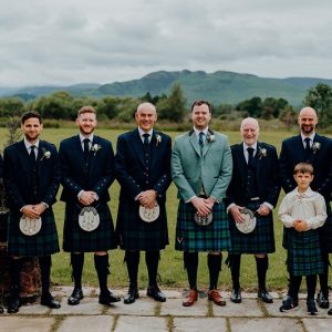 men group wearing black kilt smiling . cool environment