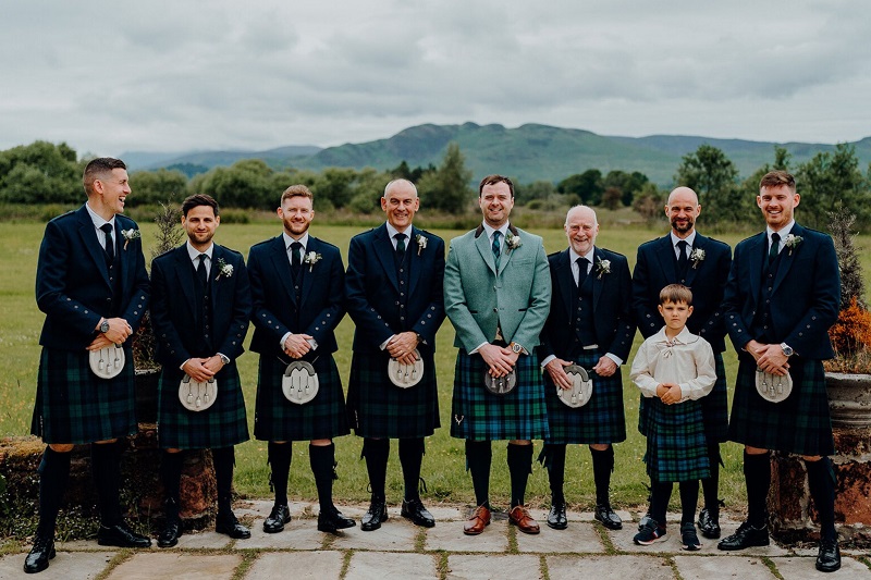 men group wearing black kilt smiling . cool environment