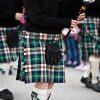 Men marching in a parade wearing Scottish kilt.