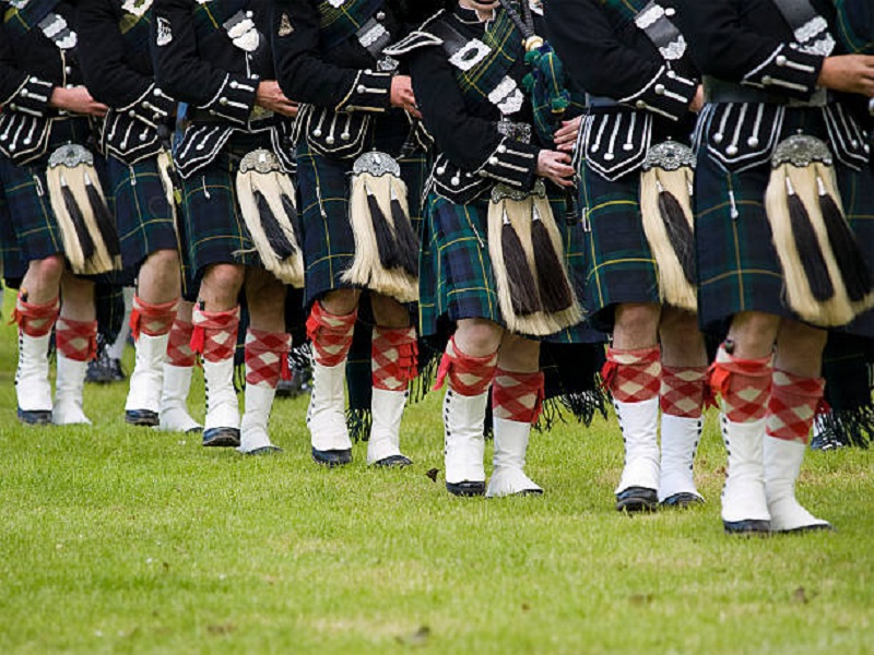 scottish men wearing tartan kilts at Highland Games event in Scotland.