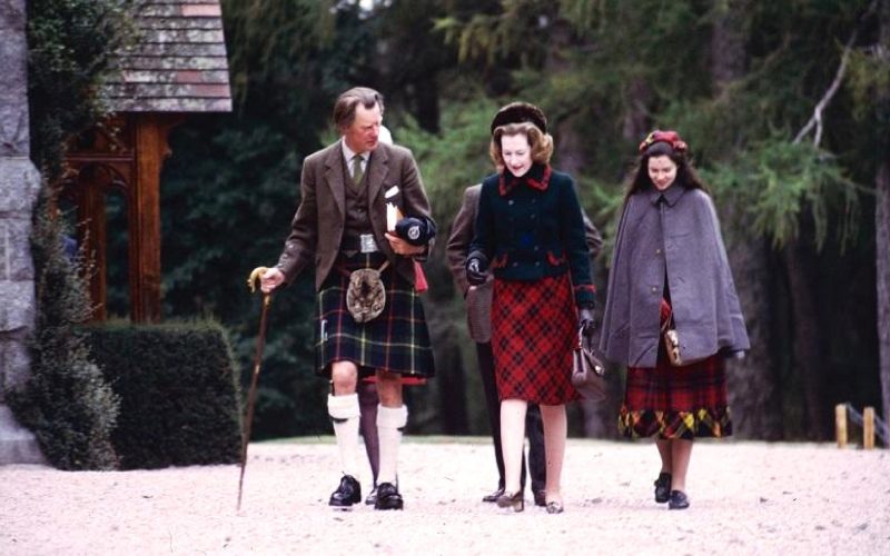 A picturesque scene featuring a man, a woman, and a joyful girl walking down the street, all donned in kilts. The girl's radiant smile adds a delightful touch to the composition. The image is captured from a slightly distant perspective, highlighting the cultural charm of kilts in a lively setting. Embodying the freedom of movement that comes with wearing a kilt.